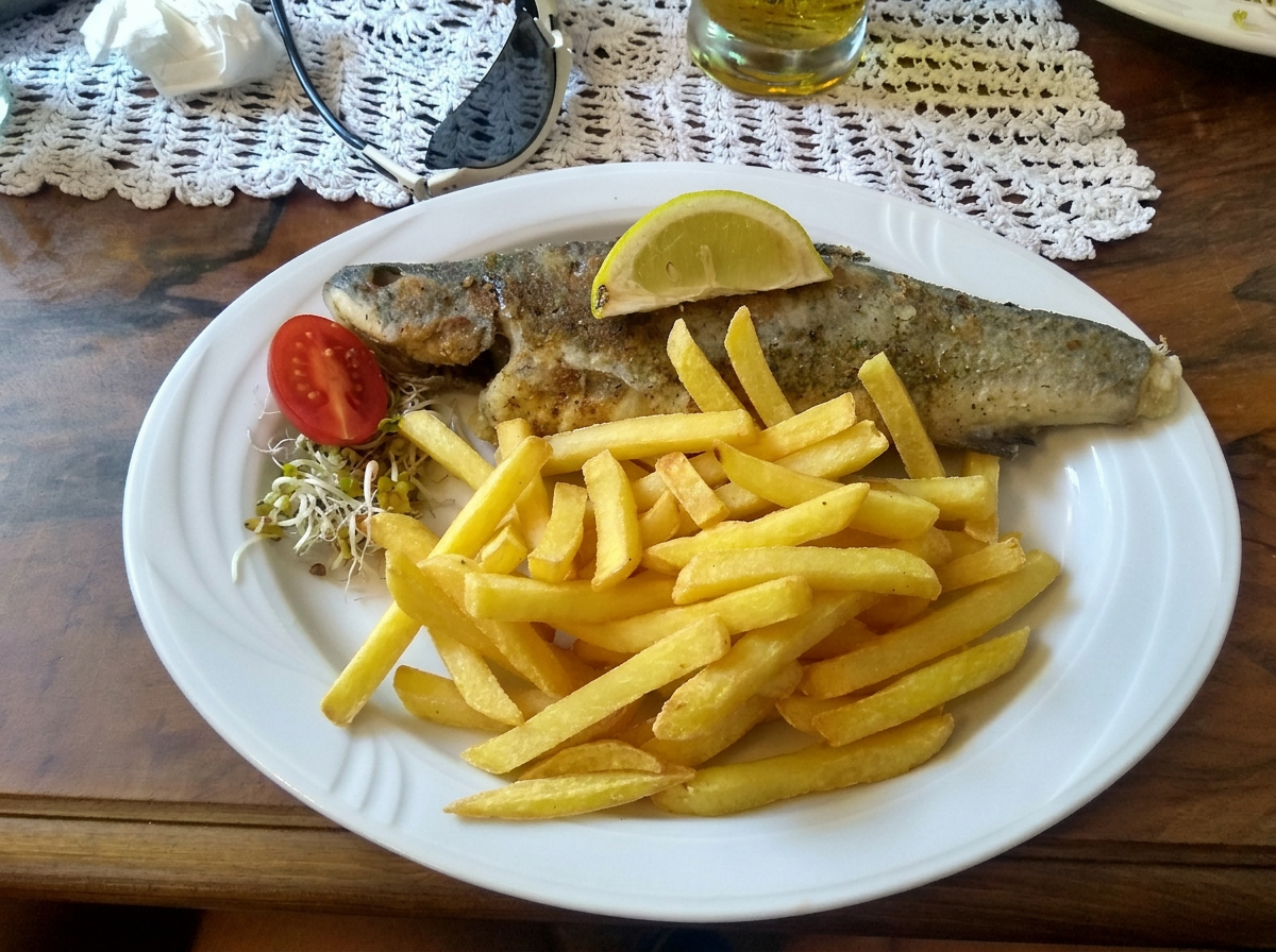 Smażony pstrąg z frytkami i cytryną na talerzu